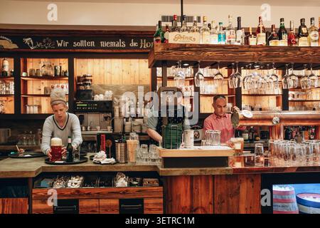 Hanover, Germany - April 21, 2026: Bartenders serving beer and drinks behind a traditional wooden bar inside a historic tavern and restaurant on Georg Stock Photo