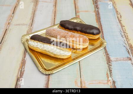 Pair of golden pepitas, one sugar-coated and one with chocolate zigzags, displayed on a patterned rectangular plate over wooden surface. Stock Photo