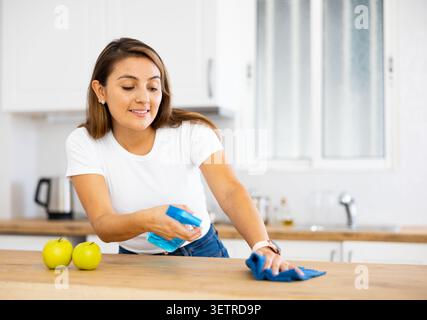 Positive young latin american woman cleaning kitchen countertop Stock Photo