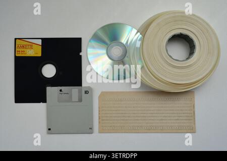 Evolution of vintage data storage: floppy disks, CD, magnetic tape reel, and punch card isolated on white background, retro tech concept Stock Photo