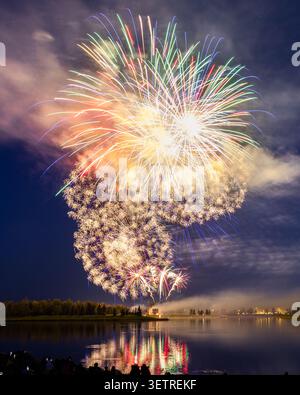 Fireworks burst over a pond at the Global Fest annual International Fireworks Festival in Calgary, Alberta, Canada. Stock Photo