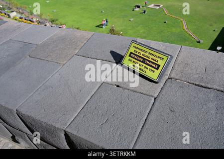 "Do not sit on the Inca wall" sign in the Coricancha (or Qorikancha) temple, Cusco, Peru. Stock Photo