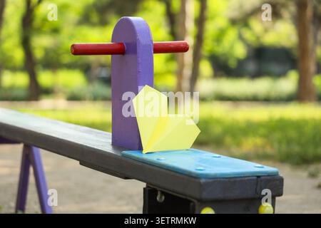 Yellow paper airplane on colorful playground seesaw Stock Photo