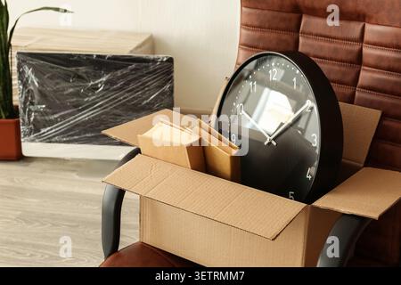 Packed office items in cardboard box on chair Stock Photo