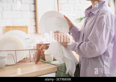 Person drying clean dishes in kitchen Stock Photo
