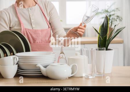 Person drying dishes in kitchen with pink apron Stock Photo
