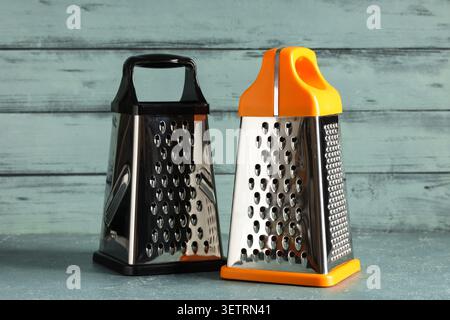 Two metal box graters with plastic handles on wooden surface Stock Photo