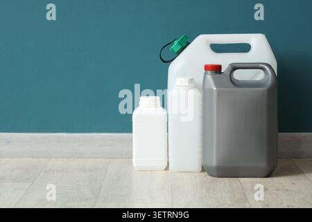 Various plastic containers and jerrycans lined up on floor against teal wall Stock Photo