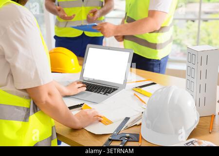 Engineers collaborating on construction project with laptop and blueprints Stock Photo