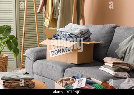 Cardboard boxes filled with folded clothes for donation on a gray sofa Stock Photo
