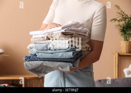 Person holding a stack of neatly folded clothes indoors Stock Photo