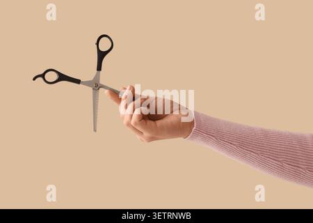 Hand holding hair thinning scissors on beige background Stock Photo