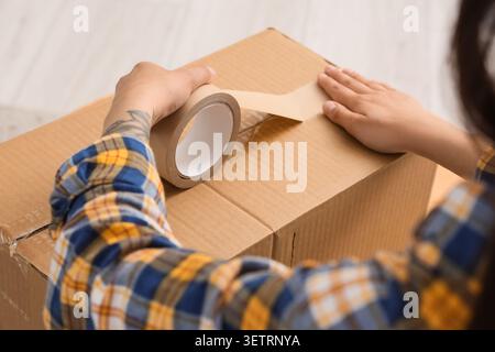 Person sealing cardboard box with packing tape Stock Photo