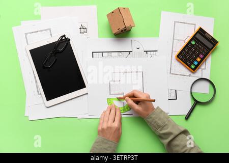 Person drawing architectural floor plans with protractor and pencil on green background Stock Photo