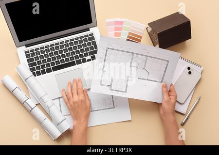 Person reviewing architectural floor plans with laptop and color swatches on desk Stock Photo