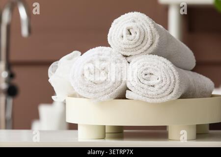 Rolled white towels arranged on a tray in a bathroom setting Stock Photo