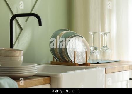 Clean dishes drying on rack in kitchen sink area Stock Photo