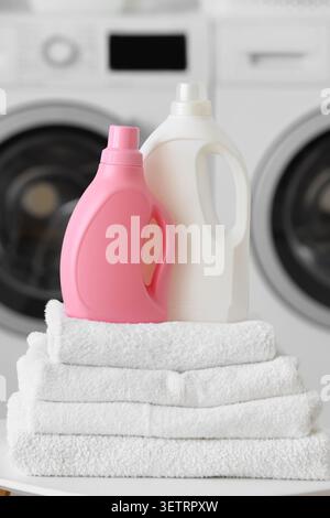 Laundry detergent bottles on folded white towels with washing machines Stock Photo