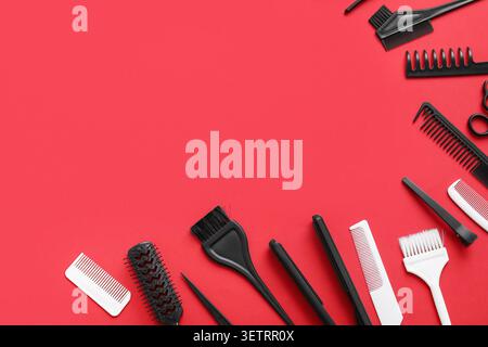 Hair styling tools and combs arranged on red background with copy space Stock Photo