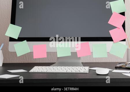 Computer monitor with colorful sticky notes on desk Stock Photo