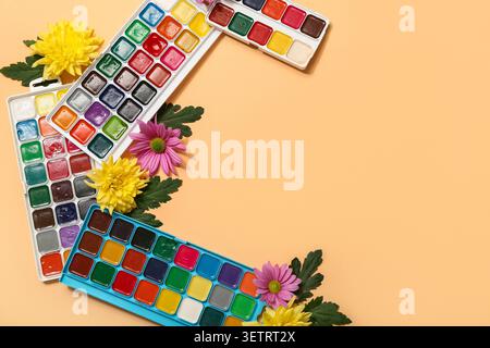 Frame made from paints and flowers on beige background Stock Photo