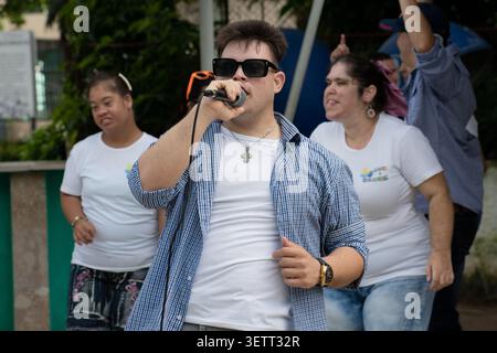 Young Cuban man with Down syndrome singing into a microphone during an outdoor community activity for the "Únicos y Brillantes" social project in Cieg Stock Photo