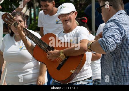 A young Cuban man with Down syndrome happily playing an acoustic guitar during a performance by the Unicos y Brillantes social project in Ciego de Avi Stock Photo