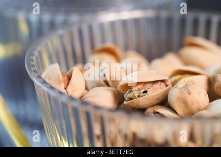 Enjoying pistachios in a clear bowl on a table Stock Photo