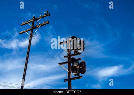Vintage railway signal and wooden telegraph pole with ceramic insulators stands under a bright blue sky with light clouds in Brazil. This historical i Stock Photo