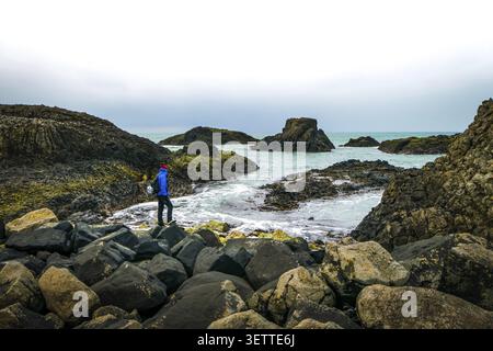 One person is stadig on rocky shore and looking to the sea. Northern Ireland Stock Photo