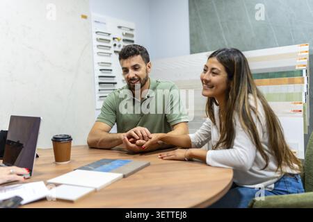 Couple consulting with an expert at a home improvement store, choosing new tiles and materials for an interior design project or house remodel, planni Stock Photo