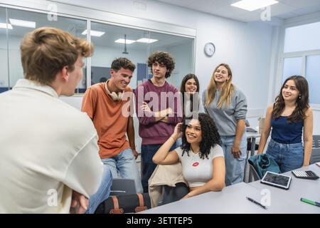 Group of happy young students engaging in a discussion and smiling together during a collaborative study session in a bright, modern university classr Stock Photo