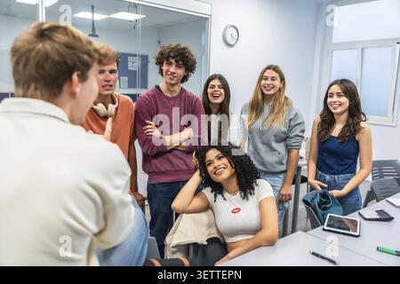 Group of happy high school students smiling while listening to a classmate explaining a concept, fostering teamwork and engaging in an active learning Stock Photo