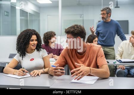 Students actively engaging and collaborating while listening to their professor in a contemporary university classroom, fostering a dynamic learning e Stock Photo