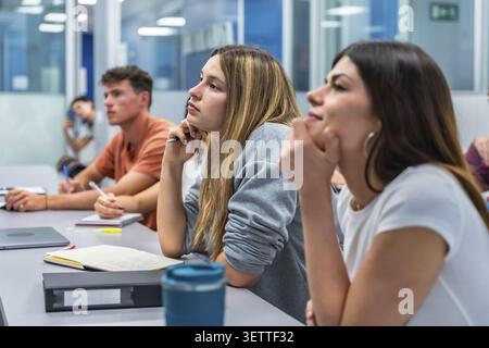 Young university students in a modern classroom focused on a lecture, taking notes and engaging in collaborative learning as they prepare for future c Stock Photo