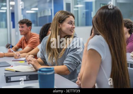 Students are actively engaged in discussion during a university lecture, focusing on communication, education, and shared learning experiences in an a Stock Photo
