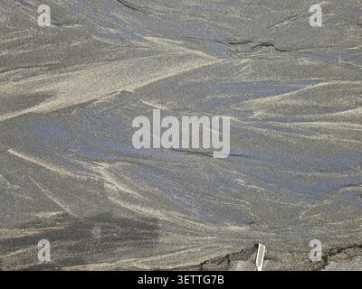 Sand with natural wave patterns in various shades of grey, alluvial sand, lava sand, sea, dark sand Stock Photo