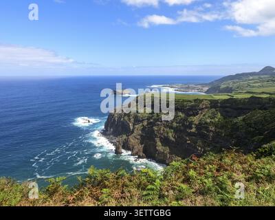 A picturesque coastal landscape with green cliffs and deep blue sea under a clear sky, overlooking coast, Sao Miguel, Azores Stock Photo