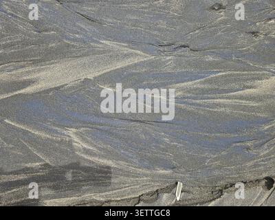 Sand with natural wave patterns in various shades of grey, alluvial sand, lava sand, sea, dark sand Stock Photo
