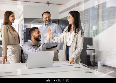 Colleagues in modern office smiling and giving high five Stock Photo