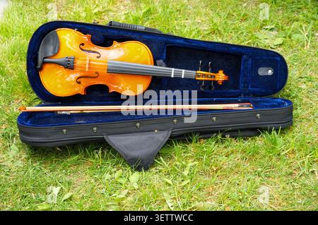 violin and bow in the blue case on the green grass background Stock Photo