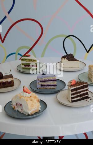 Assorted layered cake slices on ceramic plates with colorful abstract backdrop Stock Photo