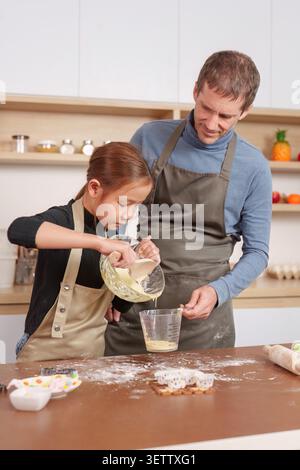 Caucasian father and Asian daughter baking together in home kitchen Stock Photo