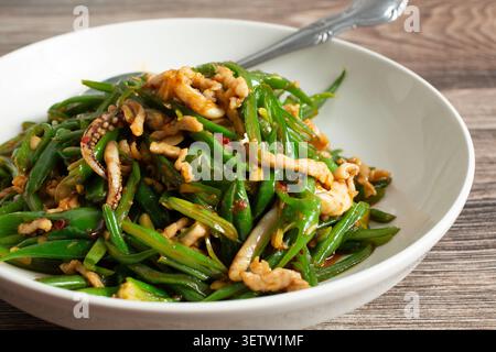 A closeup view of a bowl of pork and squid with green beans. Stock Photo