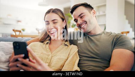 Couple, laughing and relax with phone in house, bonding or streaming video with subscription on sofa. Happy people, home and watching funny comedy Stock Photo