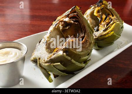 A closeup view of a plate of grilled artichokes. Stock Photo