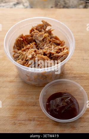 A view of a plastic container of crockpot BBQ chicken. Stock Photo
