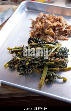 A view of a plate featuring kohlrabi greens and crockpot BBQ chicken. Stock Photo