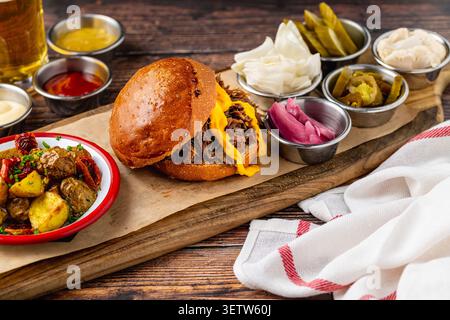 Slow cooked pulled rib beef burger with melted cheese and sides Stock Photo