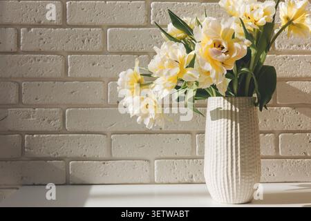 Yellow and white tulips in a vase on a kitchen counter Stock Photo